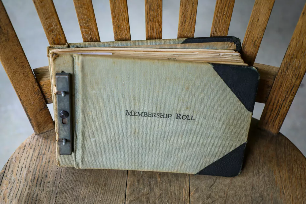 Old book with title "membership roll" on a wooden chair - Photo by Mick Haupt on Unsplash